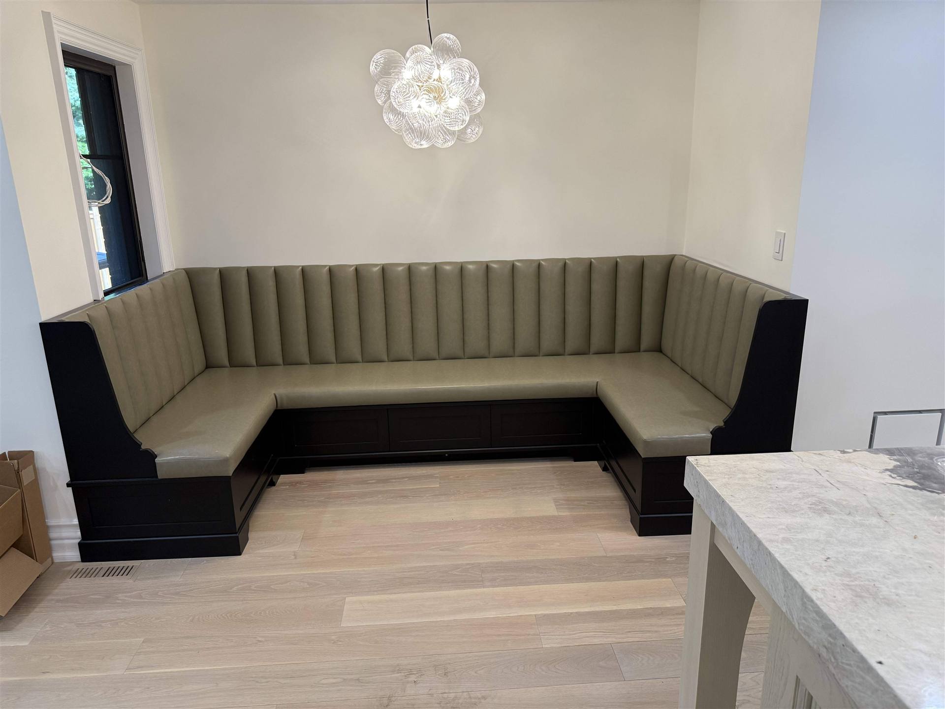 Custom olive green channel-tufted L-shaped banquette with black base