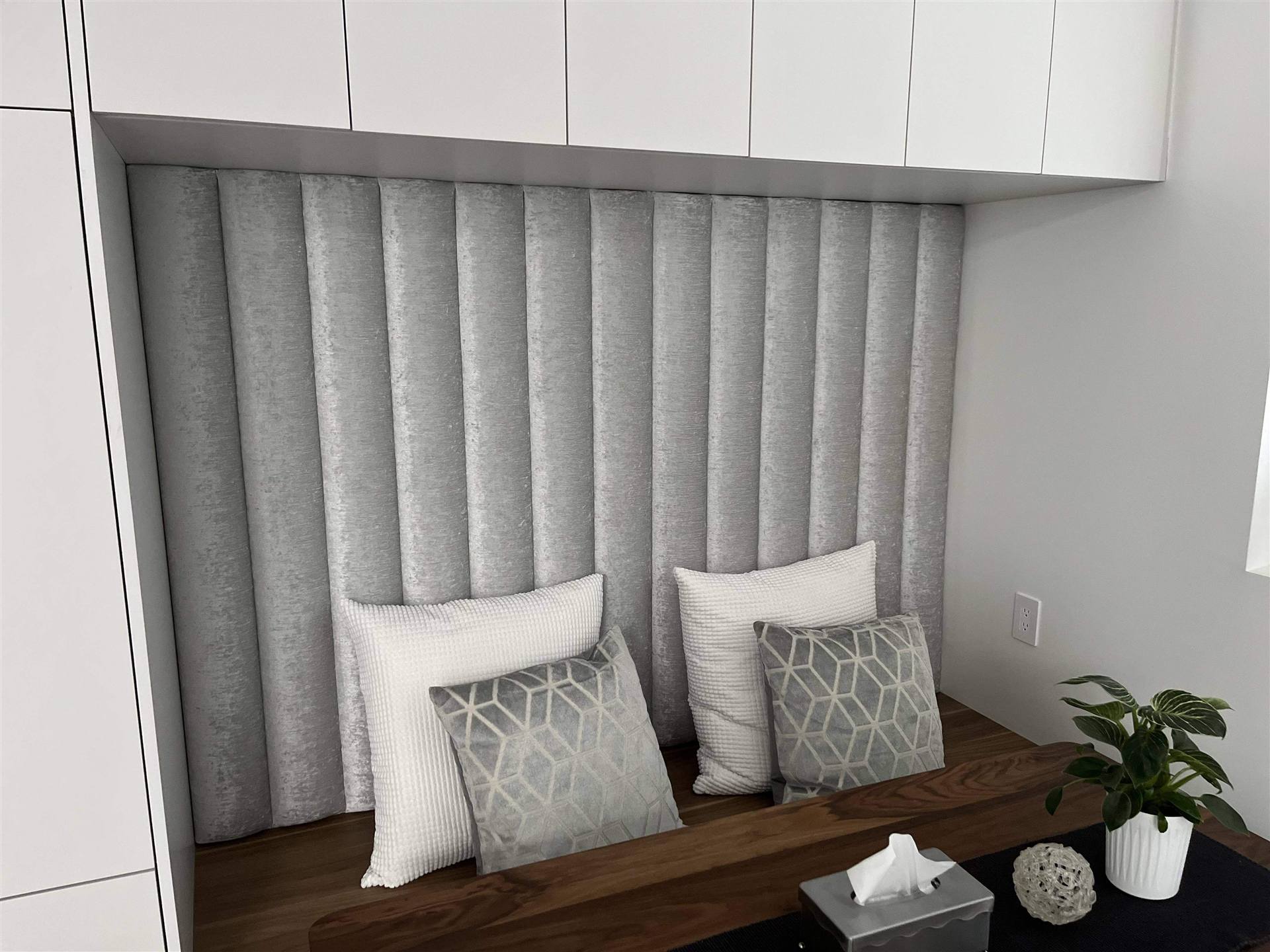 Custom grey channel-tufted upholstered wall niche with pillows