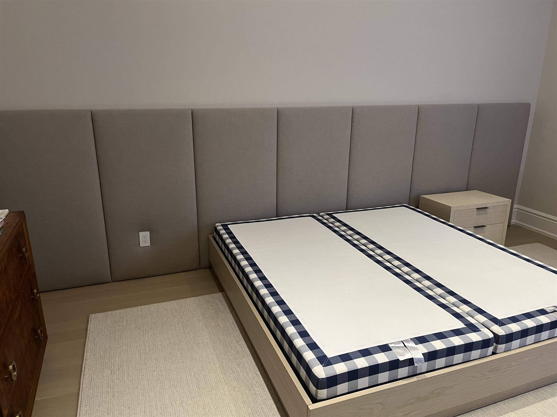 Custom grey vertical upholstered wall panels spanning full bedroom wall